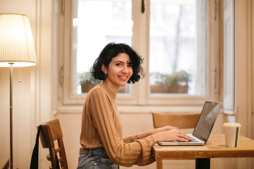 młoda kobieta siedząca przed laptopem i przygotowująca CV po angielsku